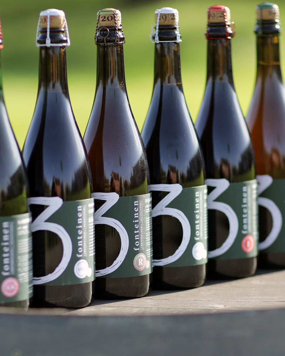 Picture of 6 beer bottles lined up on top of a barrel